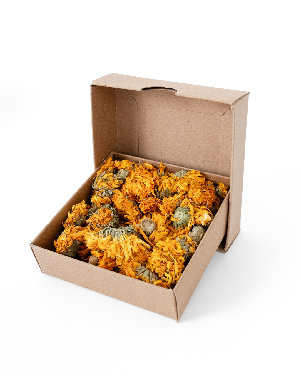 An open brown cardboard box filled with dried yellow-orange calendula flowers, photographed on a clean white background.
