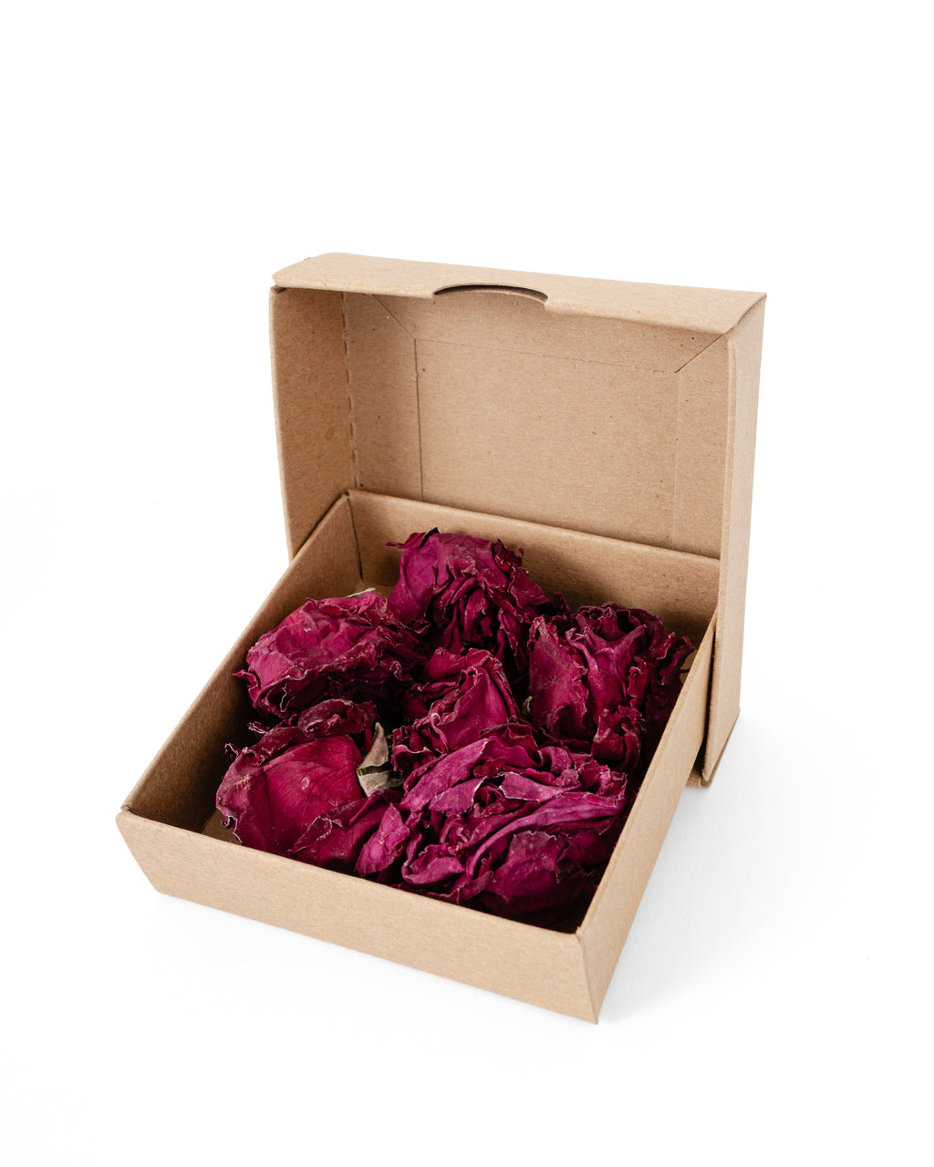 A brown cardboard gift box with its lid open, filled with dried deep magenta-purple flower petals, isolated on a white background.