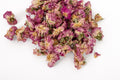 A pile of dried pink rose petals with yellow centers, scattered on a plain white background.
