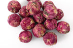 A pile of dried, pinkish-red rose flower buds rolled into a ball, arranged on a clean white background.
