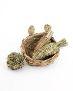 hand woven reed basket with bunny ears filled with a reed radish and timothy grass carrot. With a timothy grass ball on the side